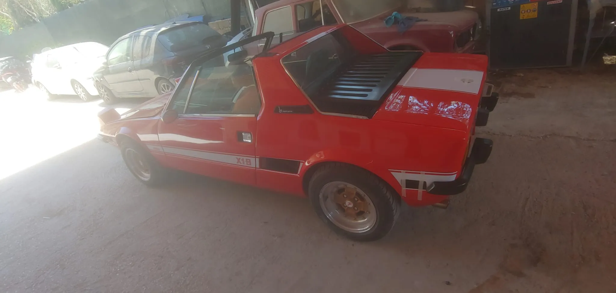 Fiat X1/9 d'epoca restaurata in rosso, vista laterale all'aperto