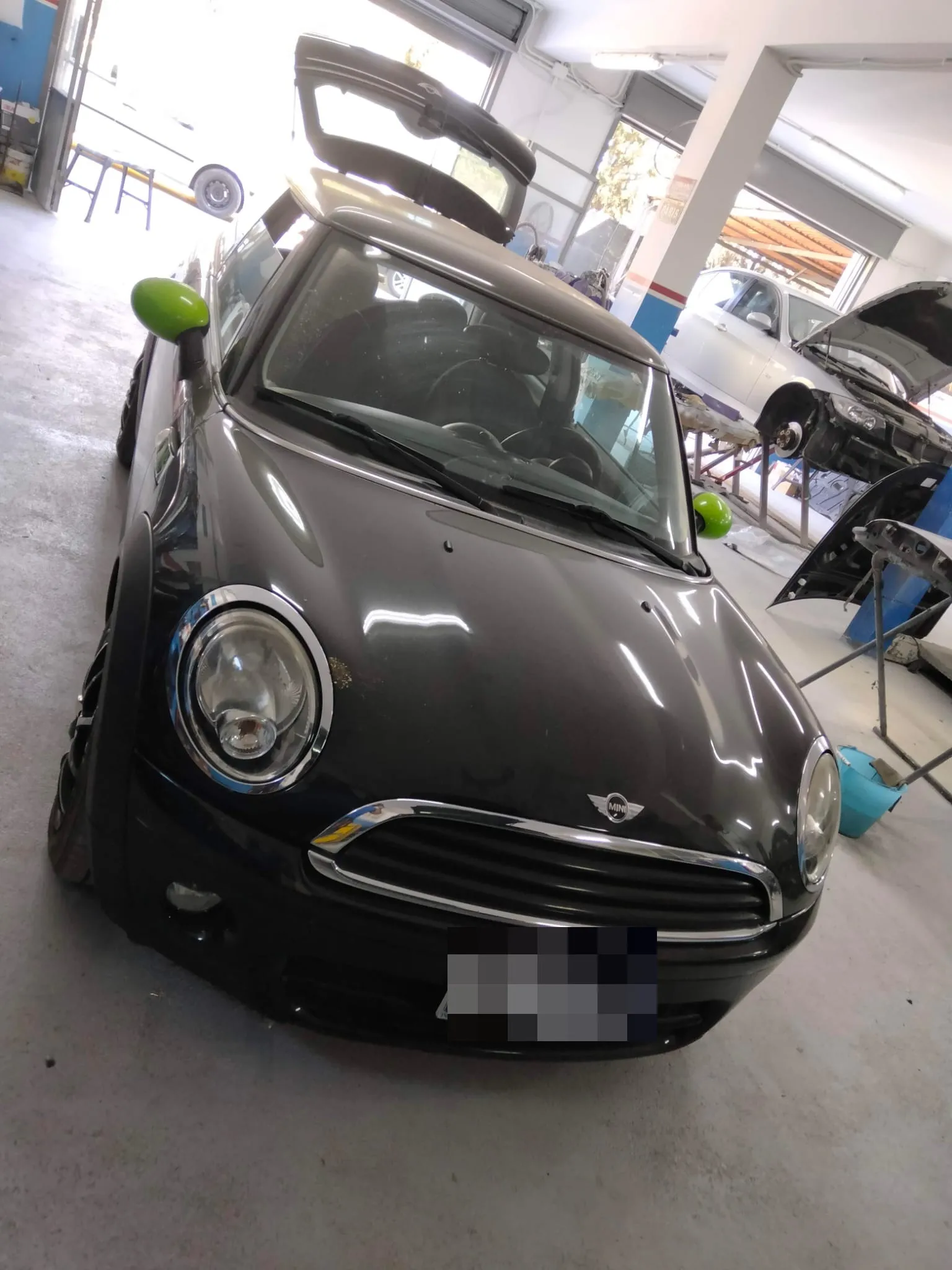 Mini Cooper nera con ammaccatura profonda sulla fiancata prima della riparazione